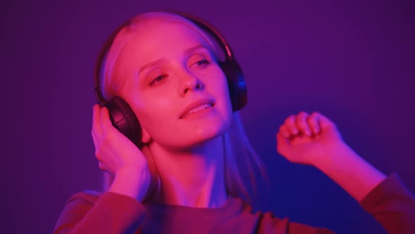 Portrait of a Young Stylish Woman Listens to Music in Big Black Headphones Dances with Pleasuree