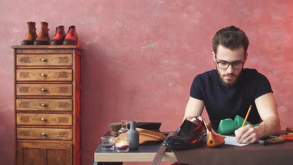 Cheerful Guy Drawing Something at Shoe Repair Shop.