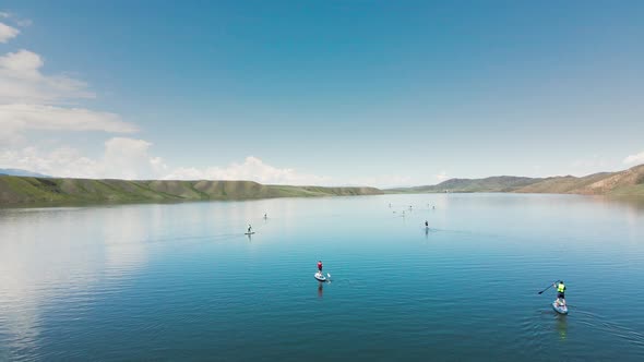 People Ride on SUP Board in the Mountain Lake