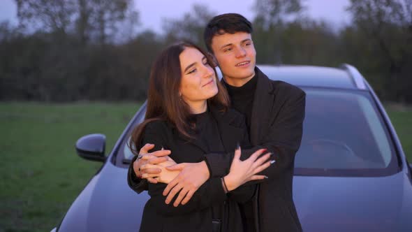 Boy and Girl Hugging and Leaning on Modern Vehicle During Romantic