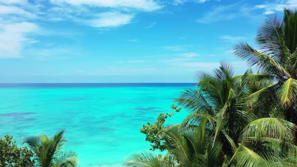 Wide angle fly over clean view of a white paradise beach and turquoise sea background in vibrant 4K