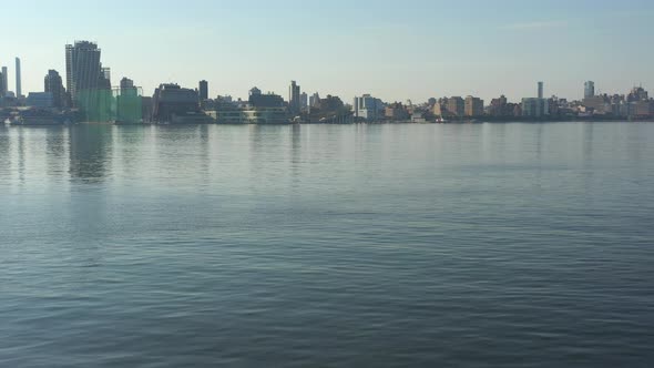 A low angle drone shot over a calm Hudson River at sunrise. The camera dolly in over the water flyin