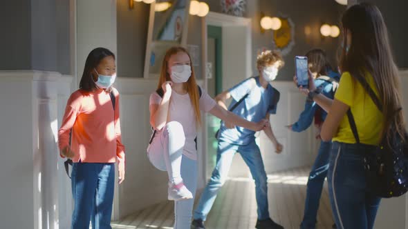 Multiracial Schoolchildren Wearing Facial Mask Relaxing in School Corridor During Break