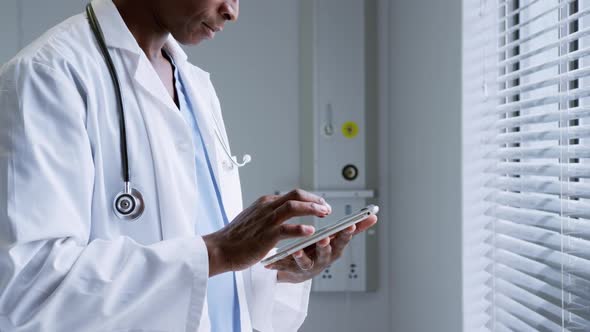 Side view of African American male doctor using digital tablet in hospital 