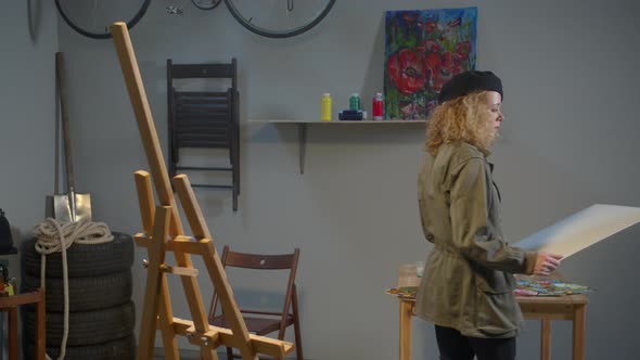 Woman Puts a Canvas on an Easel 