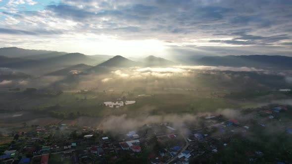 Landscape view of the city of rural village in valley on foggy day while the sun is raising by drone