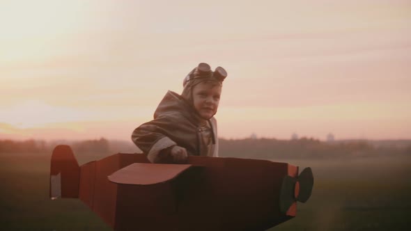 Happy Little Pilot Boy Starts To Run in Fun Cardboard Plane on Sunset Autumn Field, Playing 