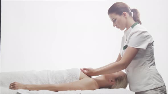 Young, healthy and beautiful woman gets massage therapy in the spa salon.