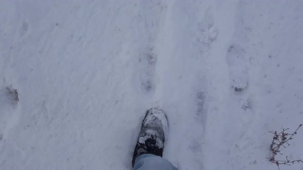 View of feet walking and running through snow in boots and wearing jeans in winter