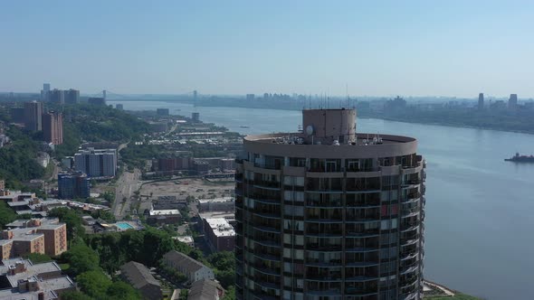 A drone view of a cylindrical building on the New Jersey side of the Hudson River, on a sunny day. T