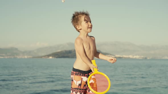 Slow Motion Video of a Boy Boy Playing Tennis on the Beach with His Parents