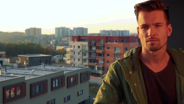 A Young, Handsome Man Stands on a Balcony, Looks Out and Then at the Camera