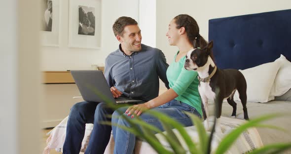 A young caucasian couple talking and paying their bills using a laptop