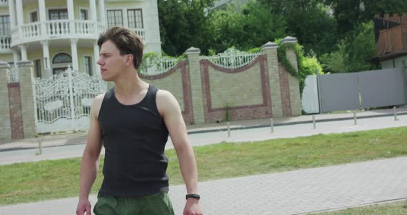 Handsome Man Walking Looking Around and Touching Smart Bracelet in Windy Day