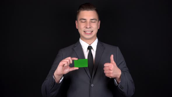 Young Businessman Presents a Bank Green Card and Shows Like with His Hand. Chromakey Green Card. Man