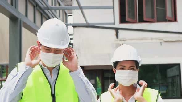 Asian workers people wearing protective face mask onsite of architecture due to COVID 19 pandemic.