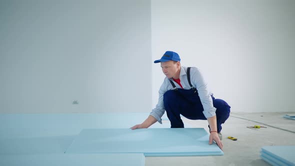 Portrait Male Builder Performs Construction Work Insulate Floor with Polyurethane Foam Before Laying