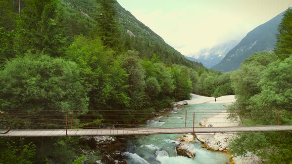 Aerial view of couple crossing a wooden bridge on bicycles at the Soca River.