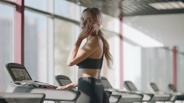 Slim Sport Woman Talking Mobile Phone in Fitness Gym. Fit Girl Walking Treadmill