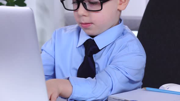 Little Boy Businessman Looking at Laptop and Keyboard Typing Tables