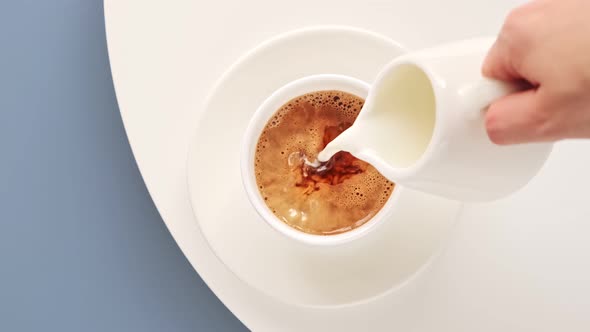 Milk cream is poured into a cup black morning coffee.