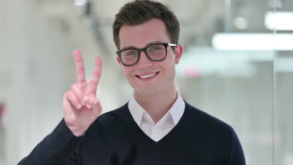 Successful Young Businessman Showing Victory Sign with Hand