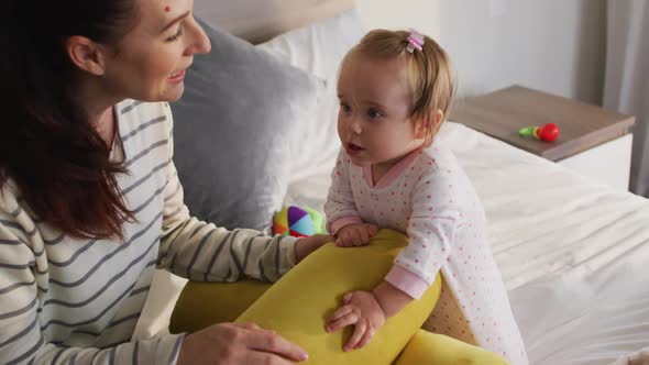 Caucasian mother and baby playing with toys on the bed at home