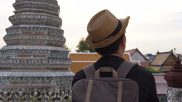 Young Asian Traveling Backpacker Looking Around in Wat Arun Temple Outdoor in Bangkok Thailand