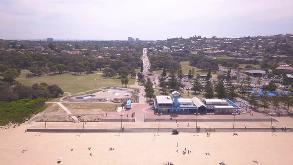 Aerial view of luxury beach with Sydney town at the background. Drone flying backwards revealing peo