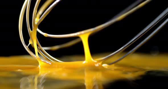 Raw Egg Stirred with a Whisk on the Table. 