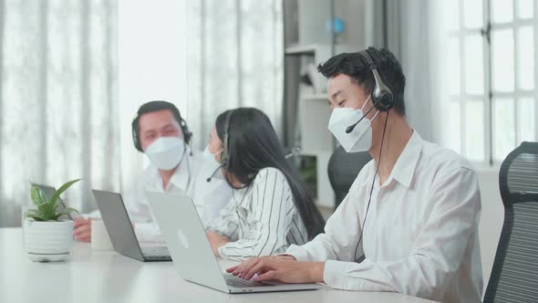 A Man Call Centre Agents Wearing Mask Working While His Colleagues Are Talking With Each Other