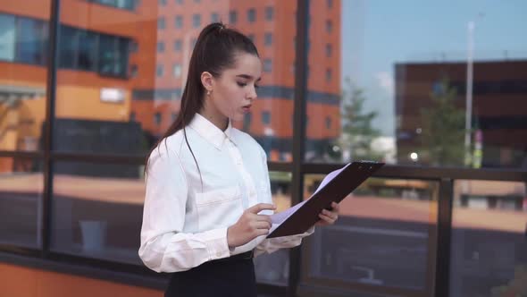 Young Business Girl Walking Near Business Center Holding Documents in Hands