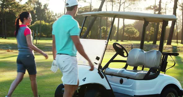 Two golf players getting into golf buggy