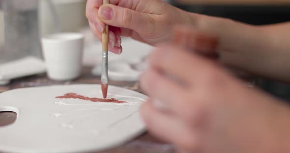 Artist Painting on Ceramic Plates During Potter Workshop