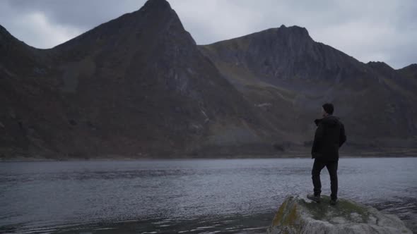 Man On Rocks Looking Over Fjord