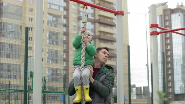 Young Boy Pretending to Climb up Rope and Dad Lifting Him alt