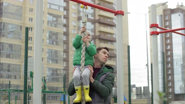 Young Boy Pretending to Climb up Rope and Dad Lifting Him