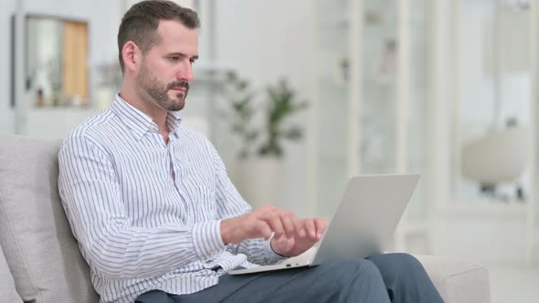 Young Man Closing Laptop and Going Away From Sofa