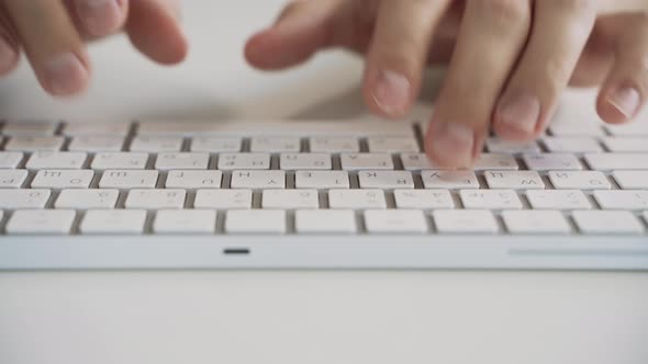 Male Hands Typing on a White Computer Keyboard