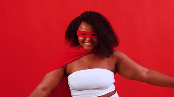 Latin Hispanic Woman in Red Eye Mask and Long Superhero Cloak in Studio Background