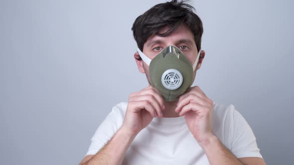 Man Puts a Respiratory Mask on Her Face on a Gray Background