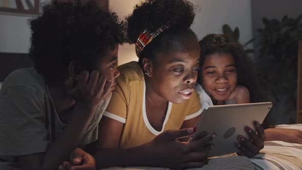 Young Aunt Reading to Siblings in Bed