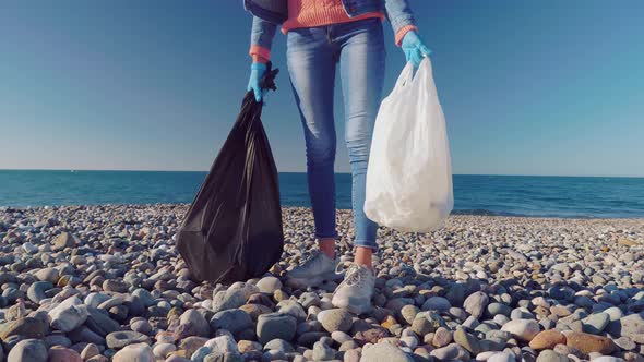 a woman collecting cleaning plastic bottles on the beach,