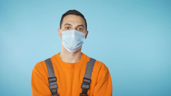 Serious Looking Man in Industrial Working Clothes and Face Mask Walking Towards Camera with Hands on