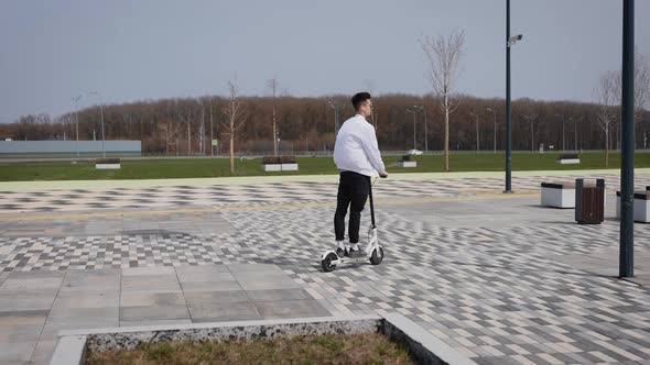 An Attractive Young Man Rides an Electric Scooter