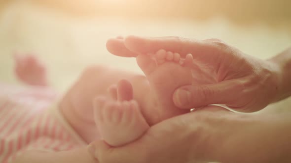 Mom Making Foot Massage for Her Infant Baby on The Bed