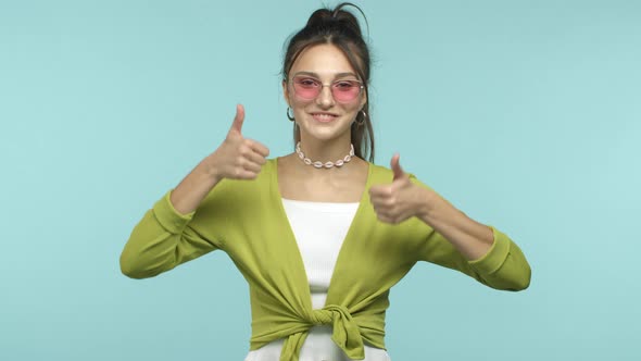 Charismatic Caucasian Girl Smiling Joyfully Showing Thumbs Up and Wink at Camera Wearing Trendy