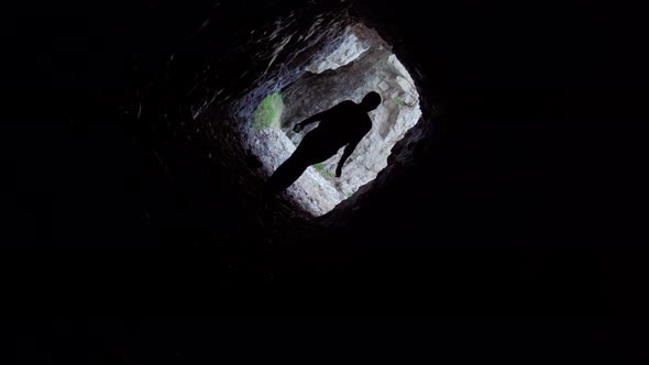 Girl Enters a Dark Cave in the Rocks