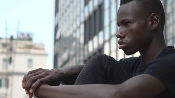 Pensive sad young african man sitting in the city