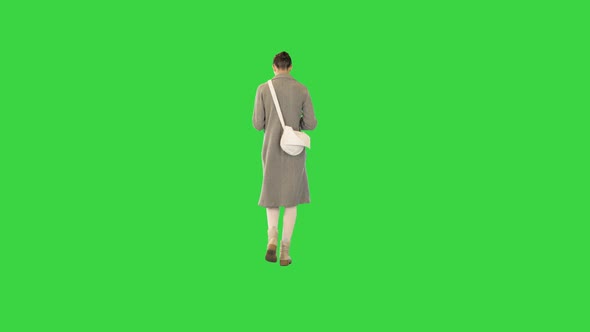 Young Woman in Stylish Clothes Walks Reading a Book on a Green Screen Chroma Key